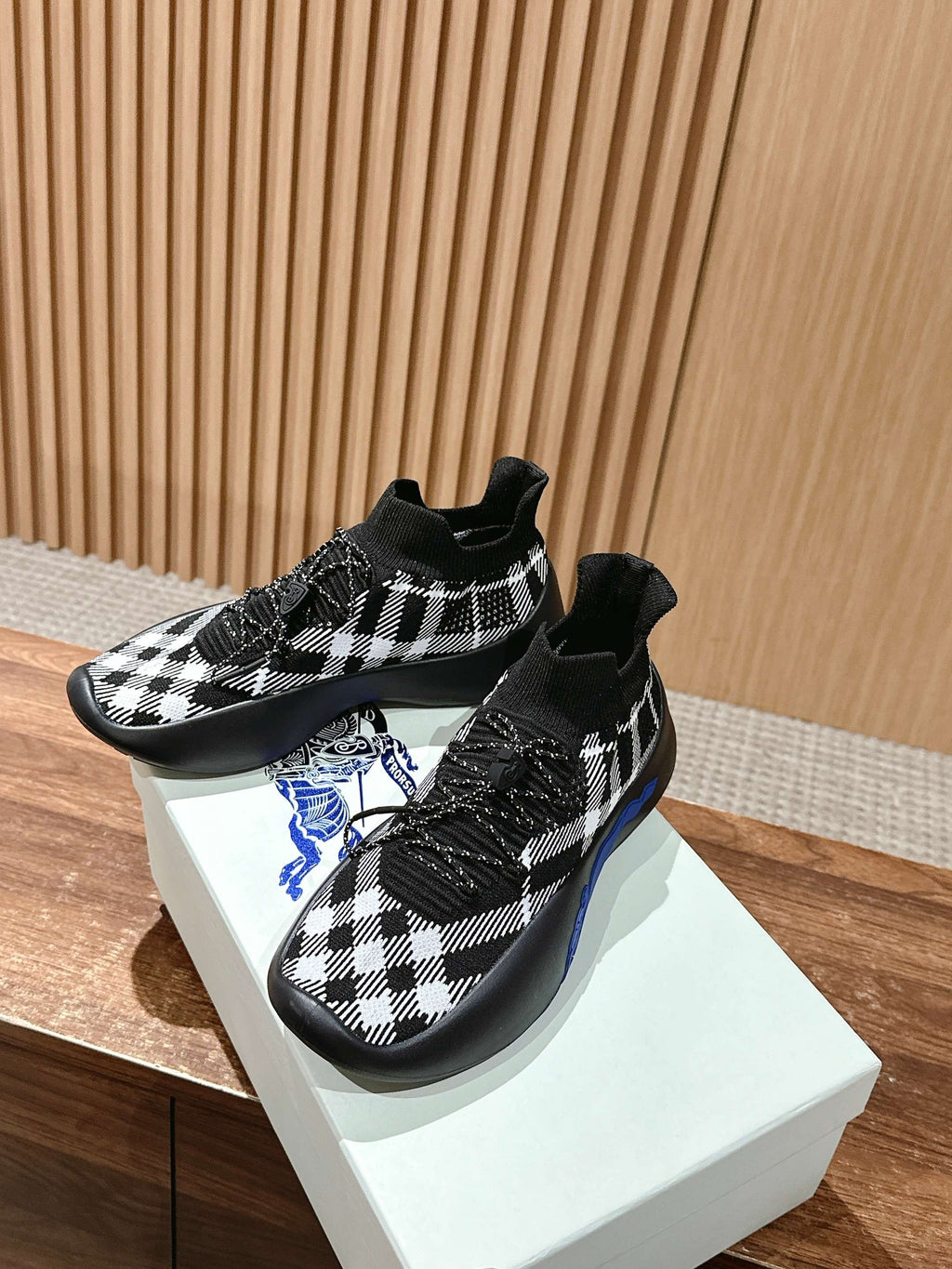 Pair of black and white check knit sneakers with lace-up front and blue sole