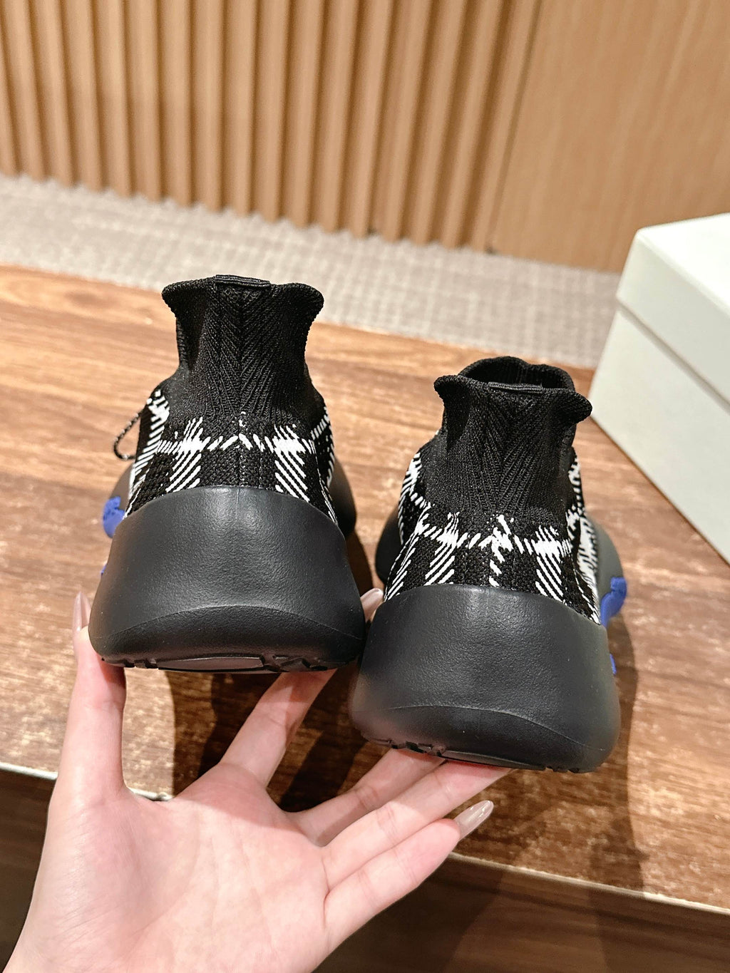 Rear view of black and white check knit sneakers with blue sole inserts