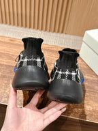 Rear view of black and white check knit sneakers with blue sole inserts