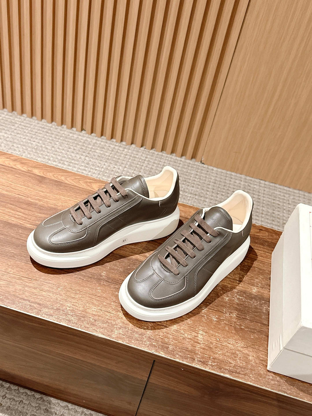 Low-top sneaker pair with lace-up design, dark taupe leather and white platform sole