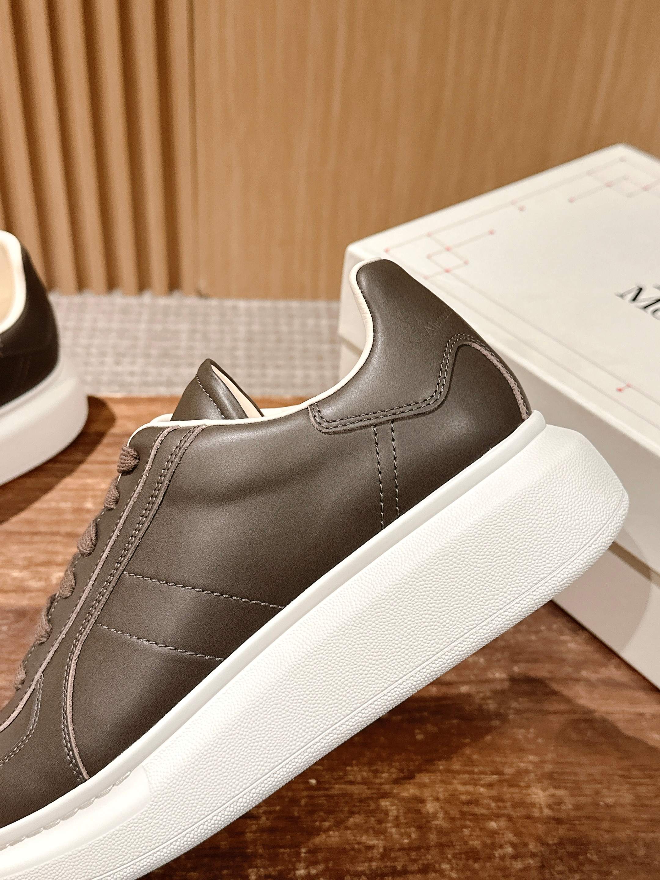 Side view low-top sneaker, dark taupe leather, brown laces and thick white sole