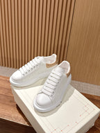 Alexander McQueen white lace-up sneakers with gold glitter heel detail, on shoebox