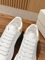 Alexander McQueen white leather sneakers with gold glitter trim, side-by-side view