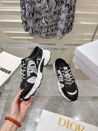 Dior black lace-up sneaker held in hand with white side panels