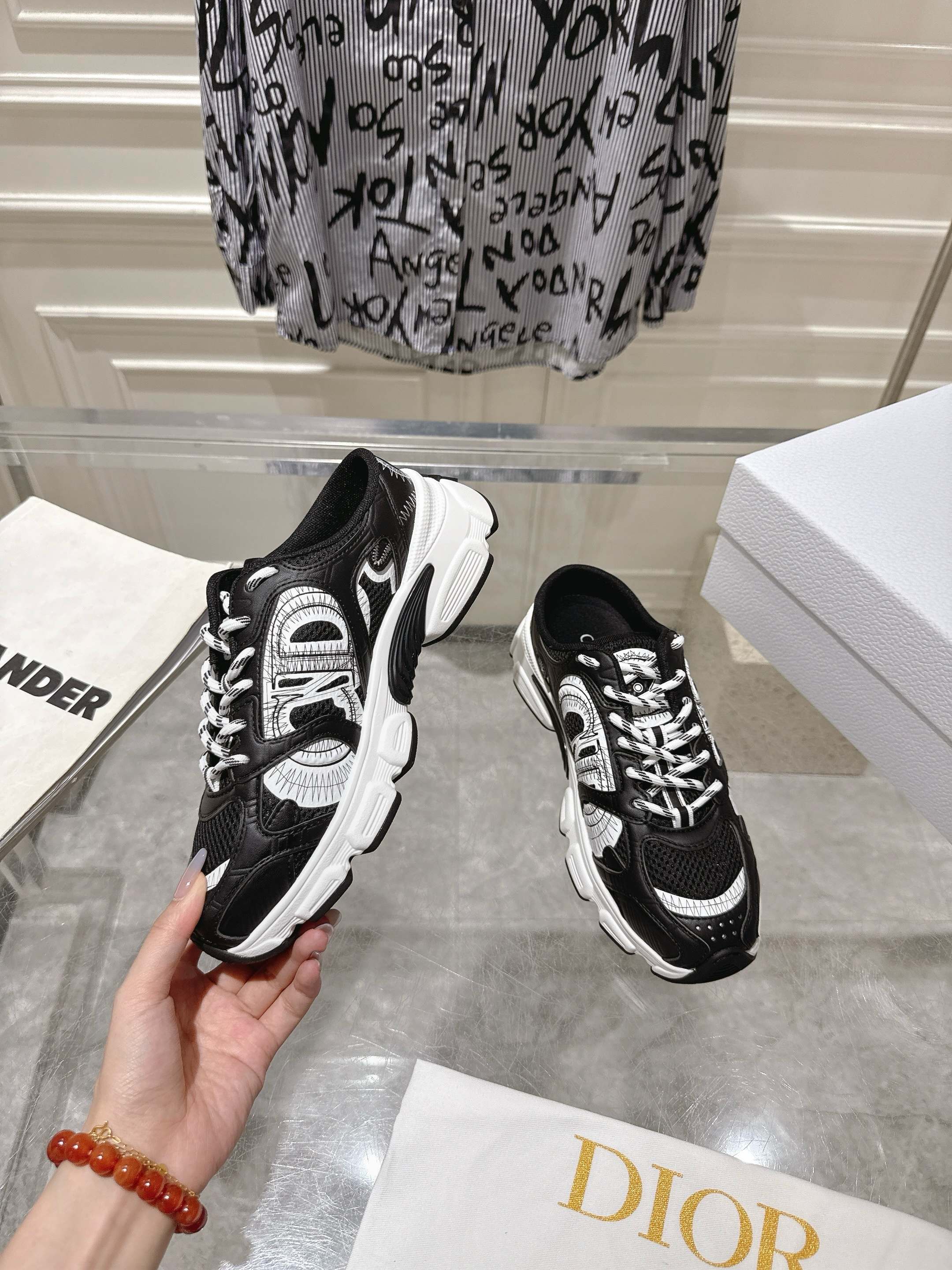 Dior black lace-up sneaker held in hand with white side panels