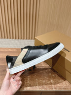 Black sneakers with beige checkered side panel and white sole, hand holding.