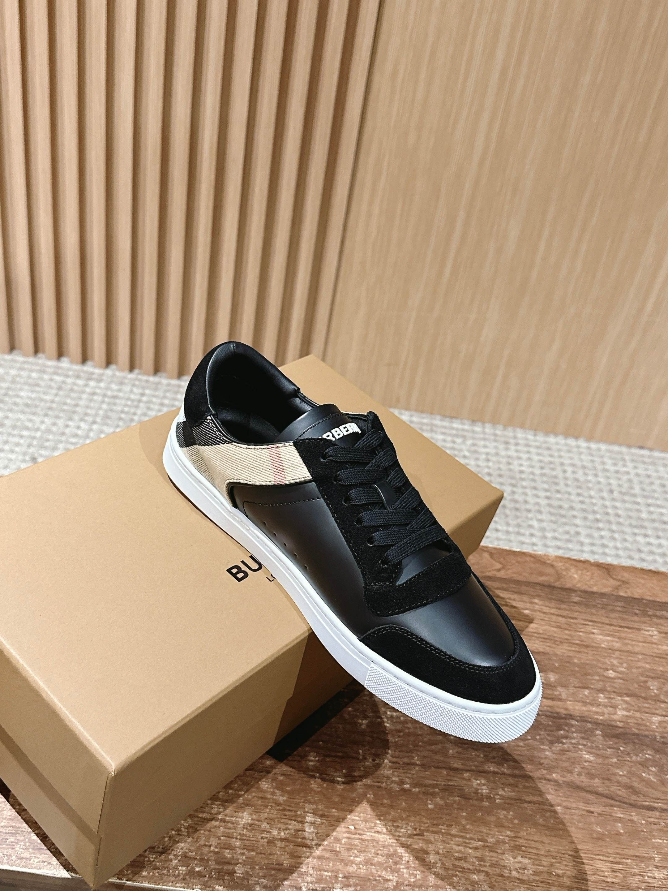 Black lace-up low-top sneakers with white sole, resting on shoe boxes, side view.