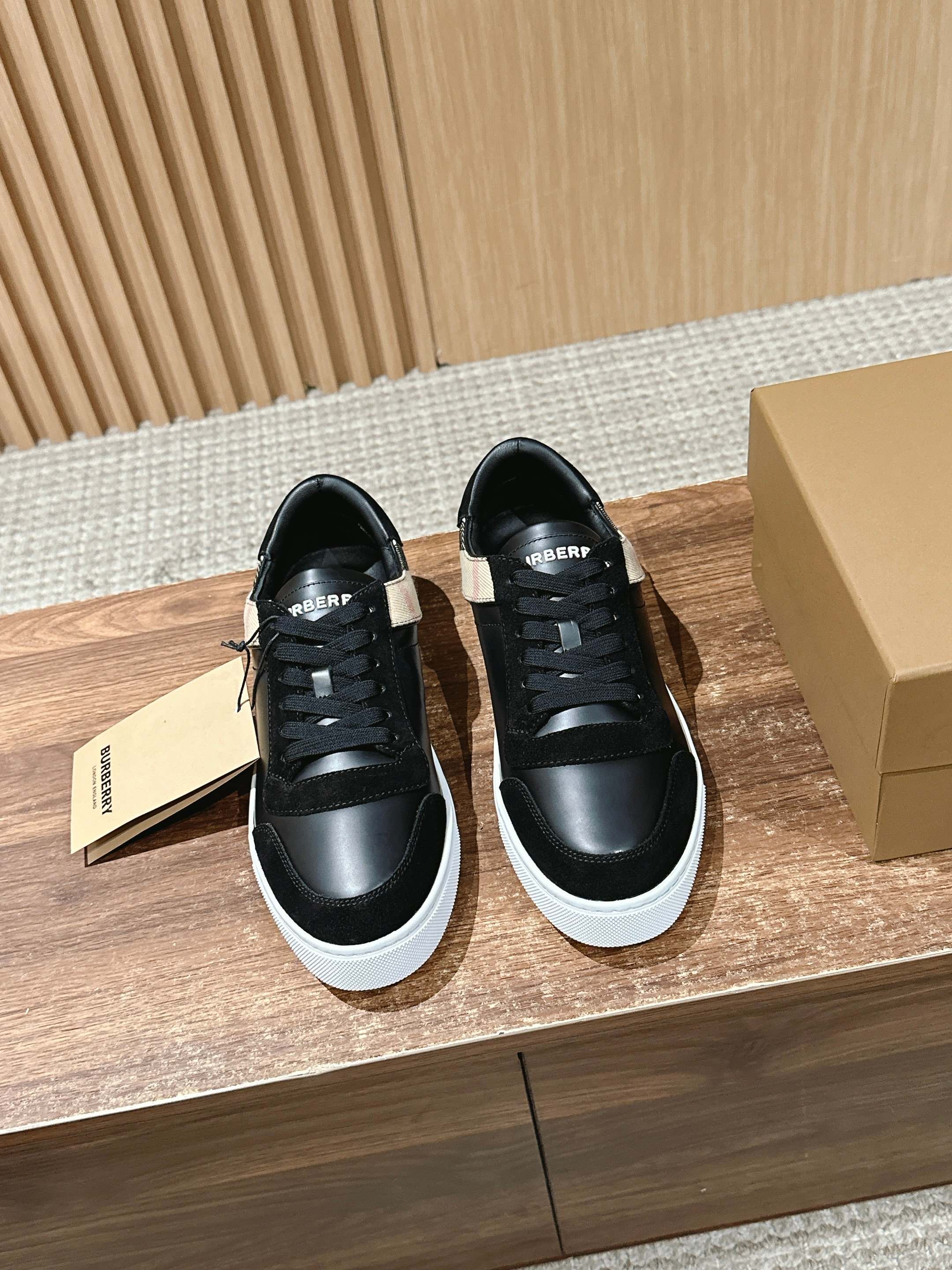 Black Burberry lace-up sneakers with white rubber sole, front view.