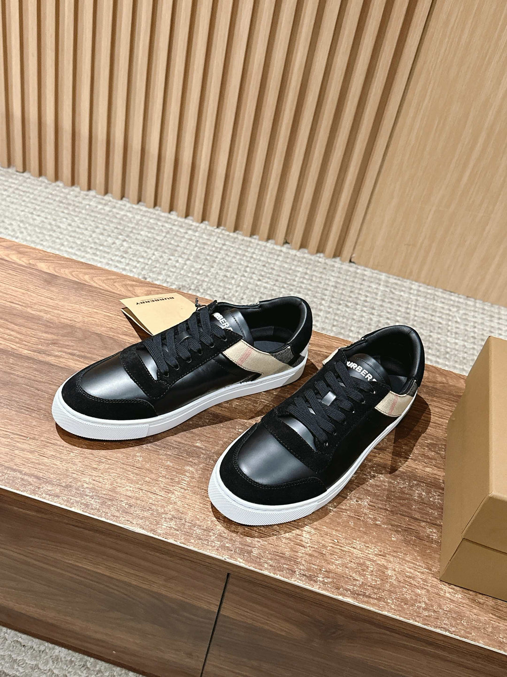 Black lace-up low sneakers with white sole and checkered side panel, angled view.