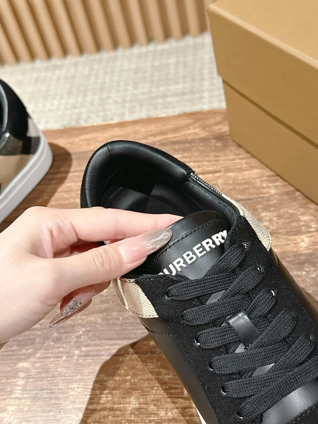 Black sneaker tongue with 'BURBERRY' lettering and lace-up front, close-up.