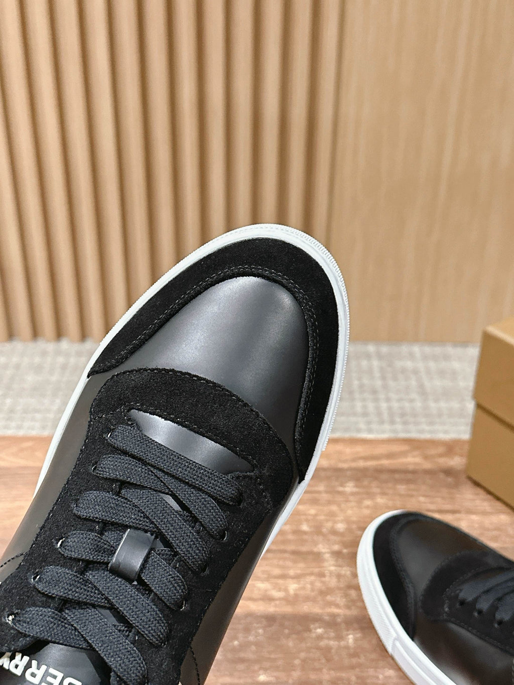 Black lace-up sneaker upper with textured toe cap and white-trim collar detail.
