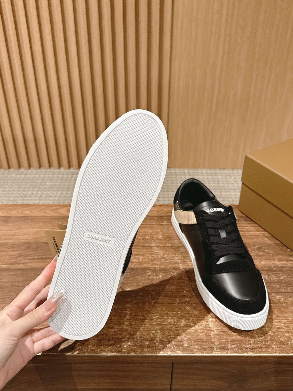 White rubber outsole and black lace-up sneakers with white sole, underside view.