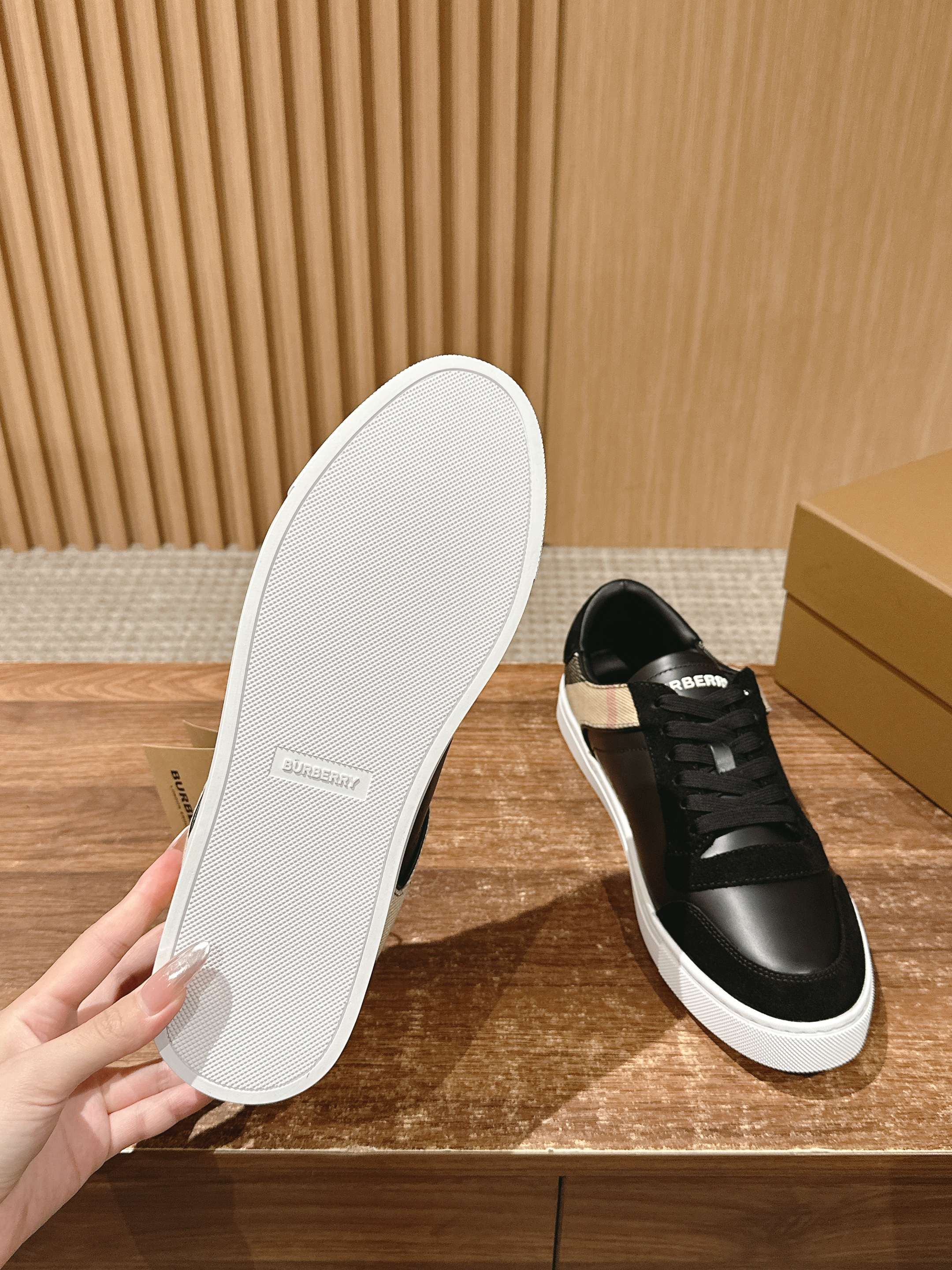 White rubber outsole and black lace-up sneakers with white sole, underside view.
