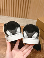 Black sneakers with checkered fabric lining and white heel trim, rear view.