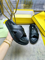 Black slide sandals with wide crisscross straps and textured sole