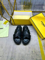 Black slide sandals with wide X straps and open toe on yellow box