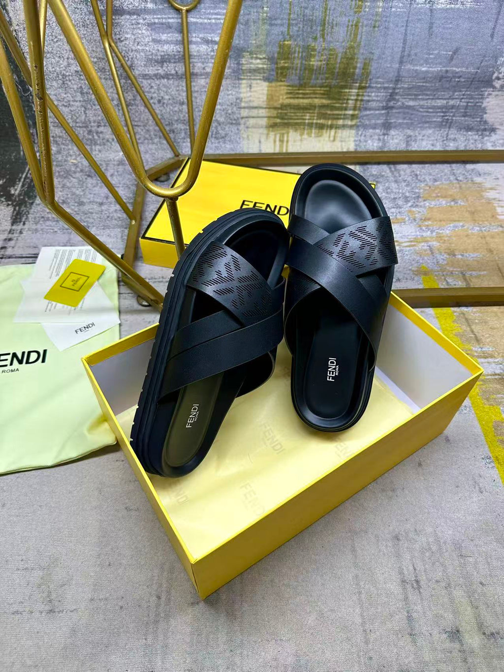 Black slide sandals with wide X straps and thick sole, shown on box
