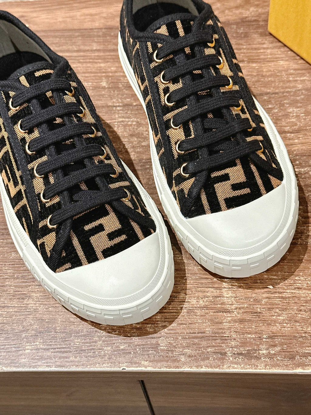 Two Fendi unisex sneakers side by side, black FF logo uppers and white rubber soles