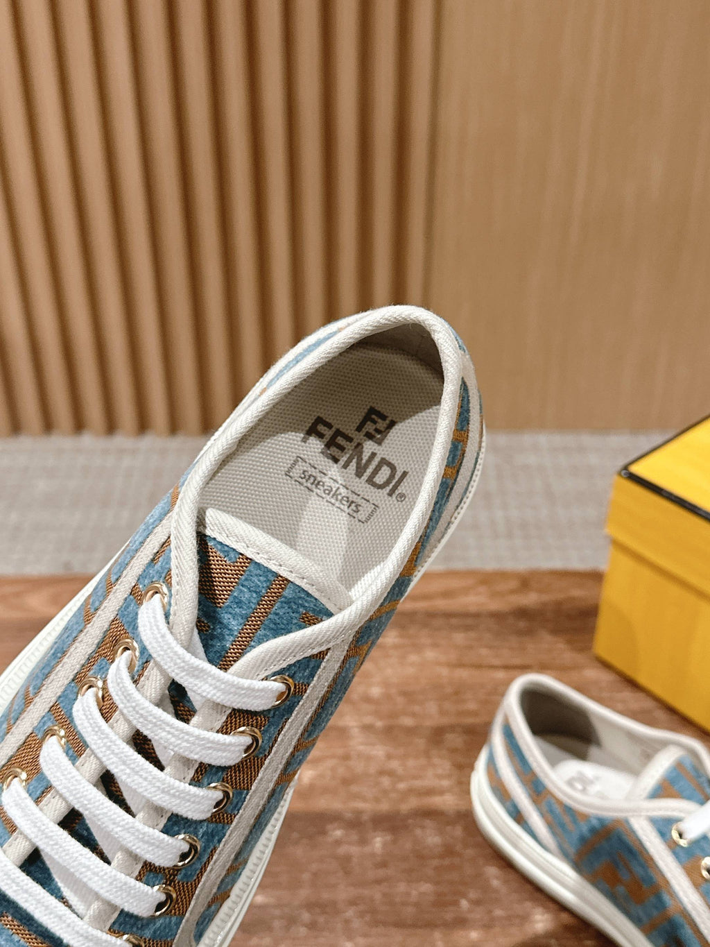 Fendi sneaker with blue logo canvas, white laces, and Fendi label on tongue