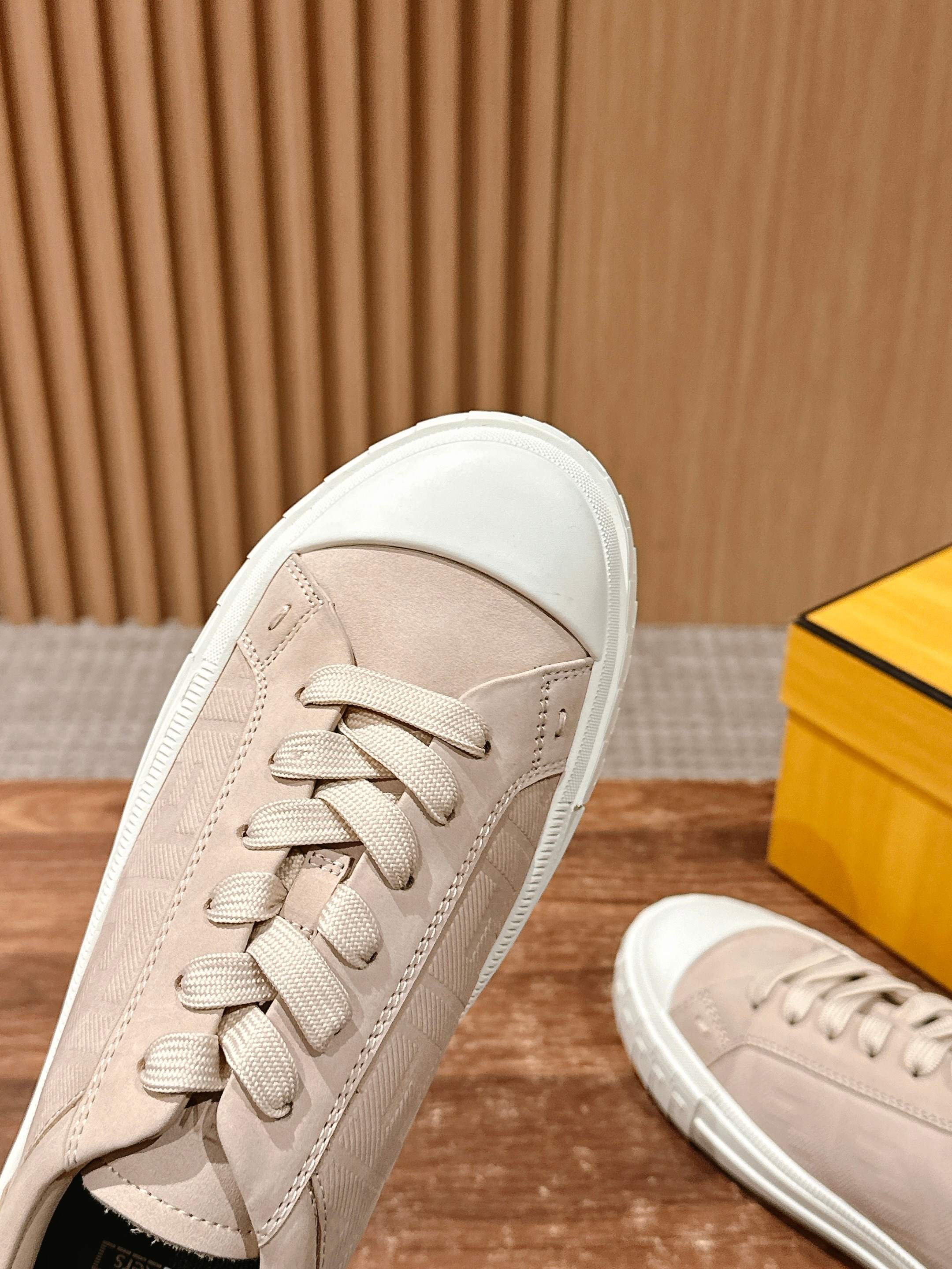 Beige sneakers, close-up side view with lace-up top and white rubber edge, unisex.