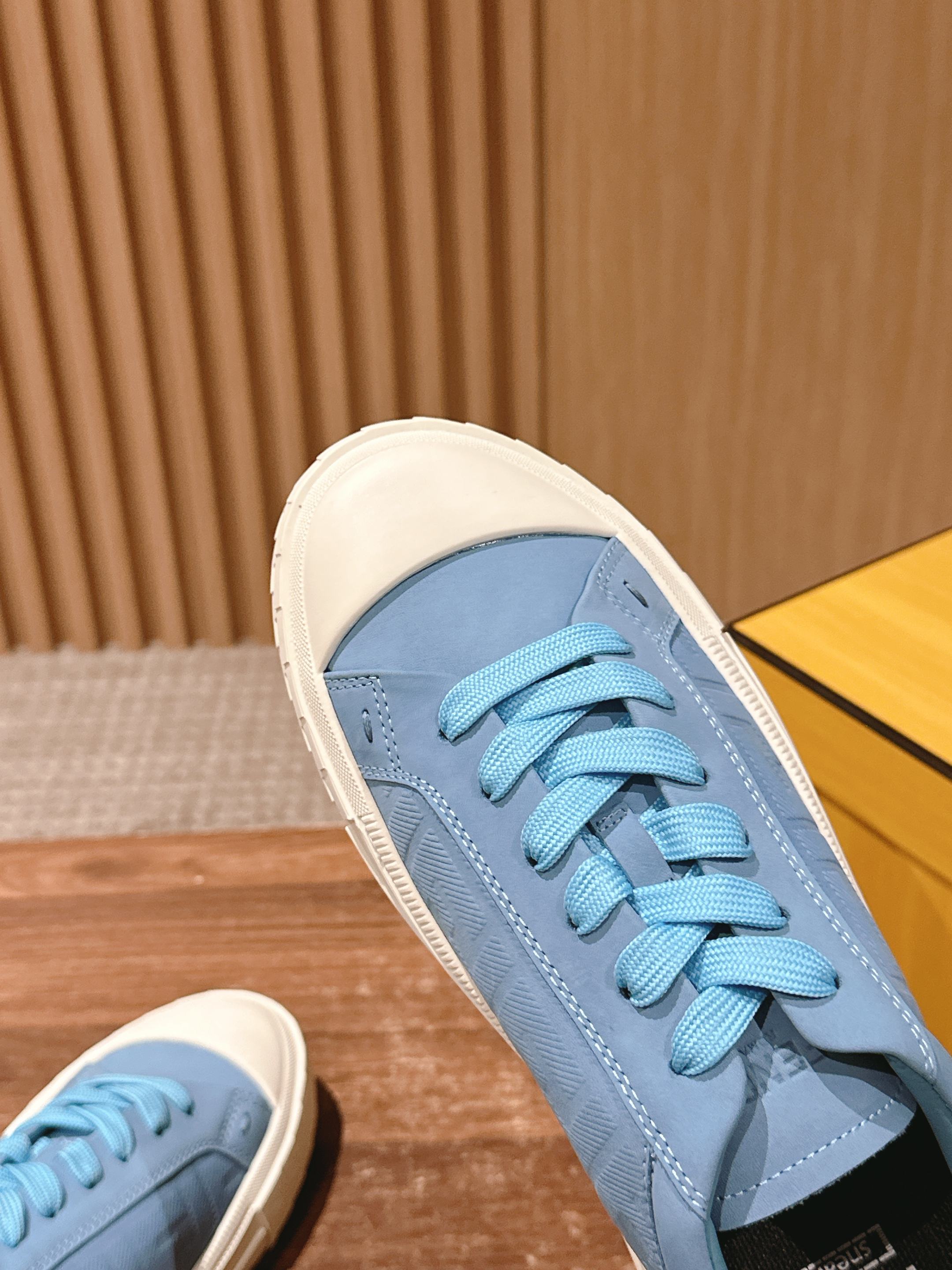 Light blue sneakers with blue laces and off-white rubber cupsole.