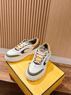 Pair of white Fendi sneakers with orange laces, dark eyelets, and yellow trim
