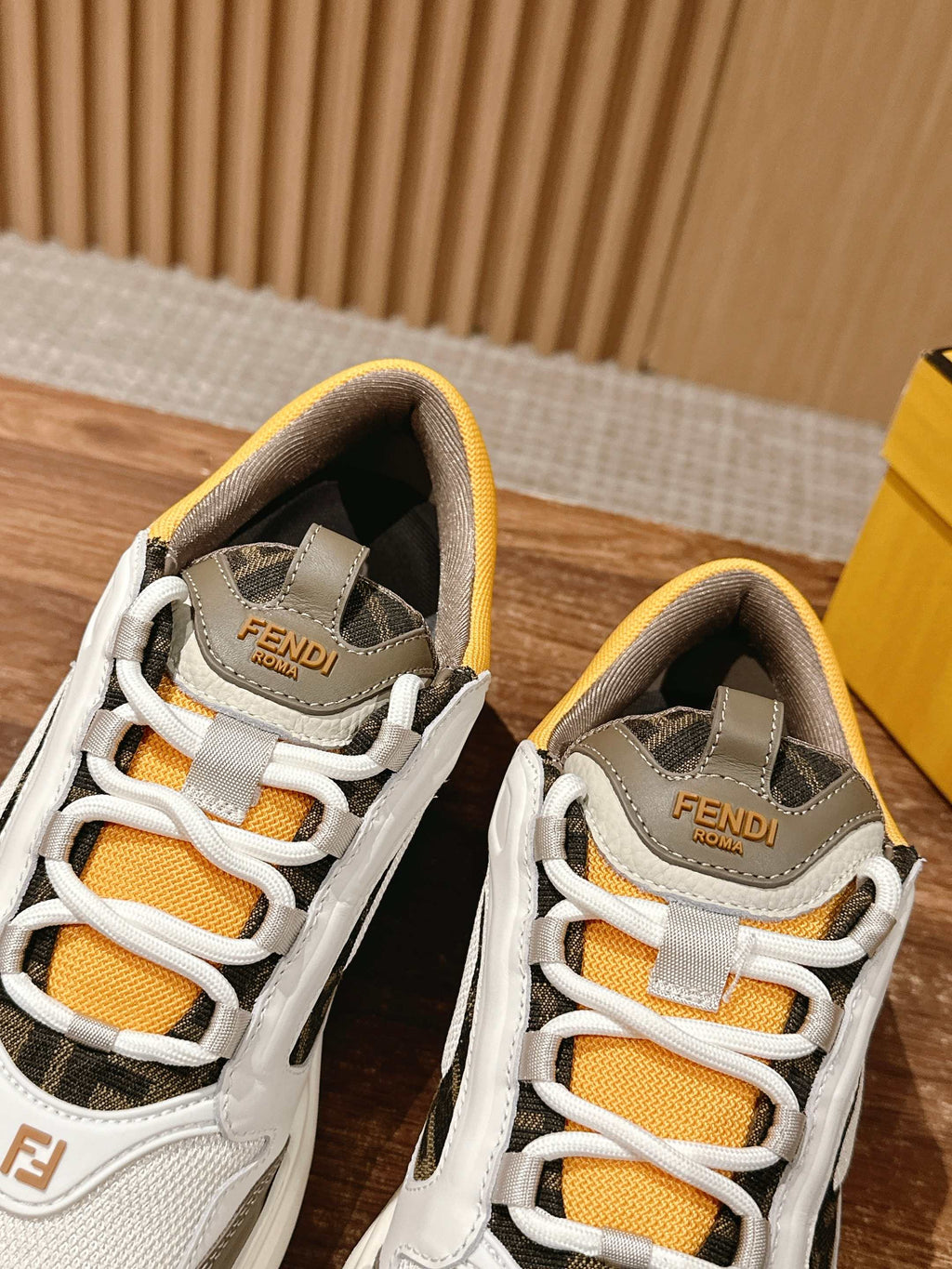 Fendi unisex sneakers close-up, white uppers with orange laces and FENDI heel patch