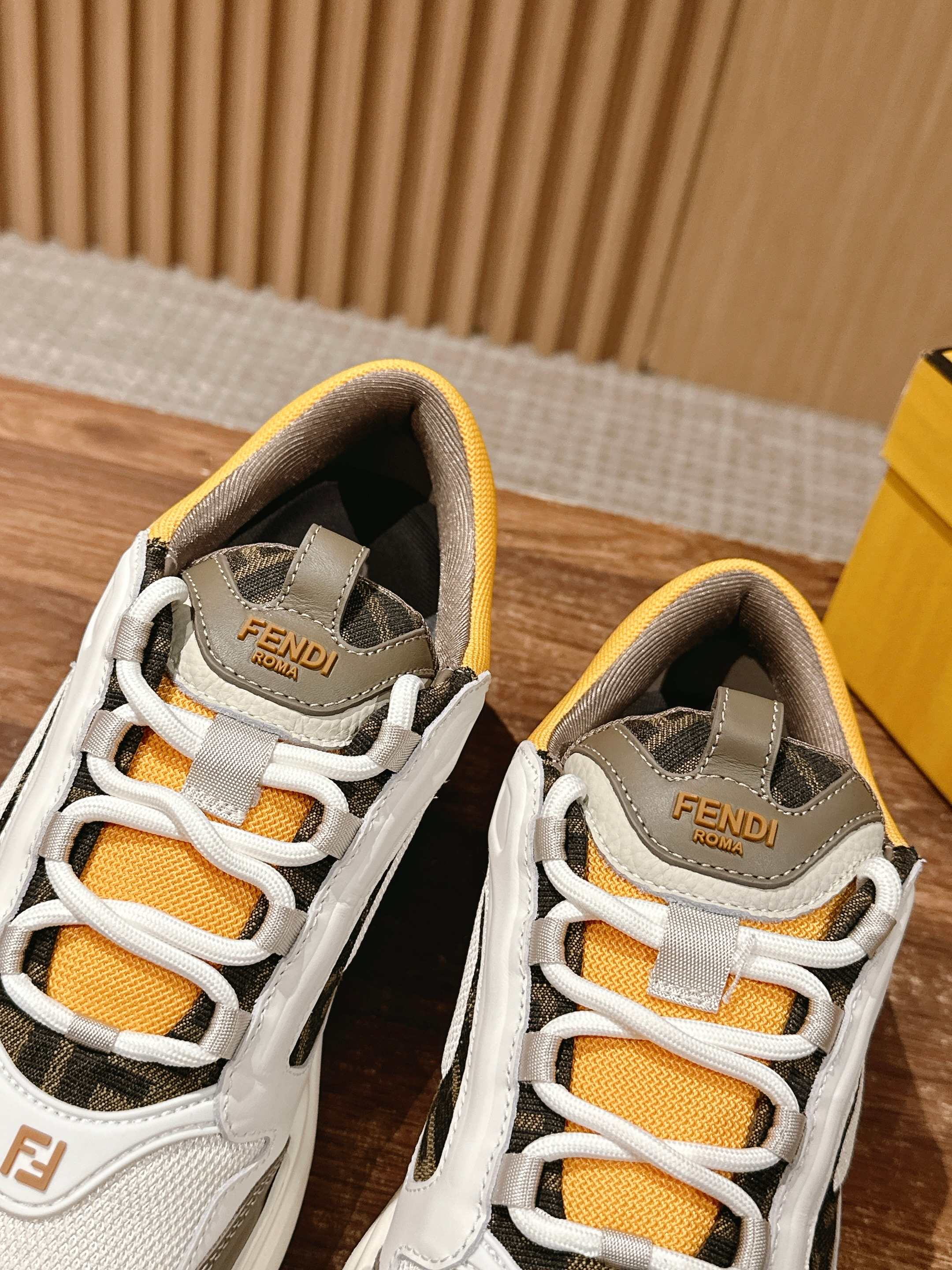 Fendi unisex sneakers close-up, white uppers with orange laces and FENDI heel patch