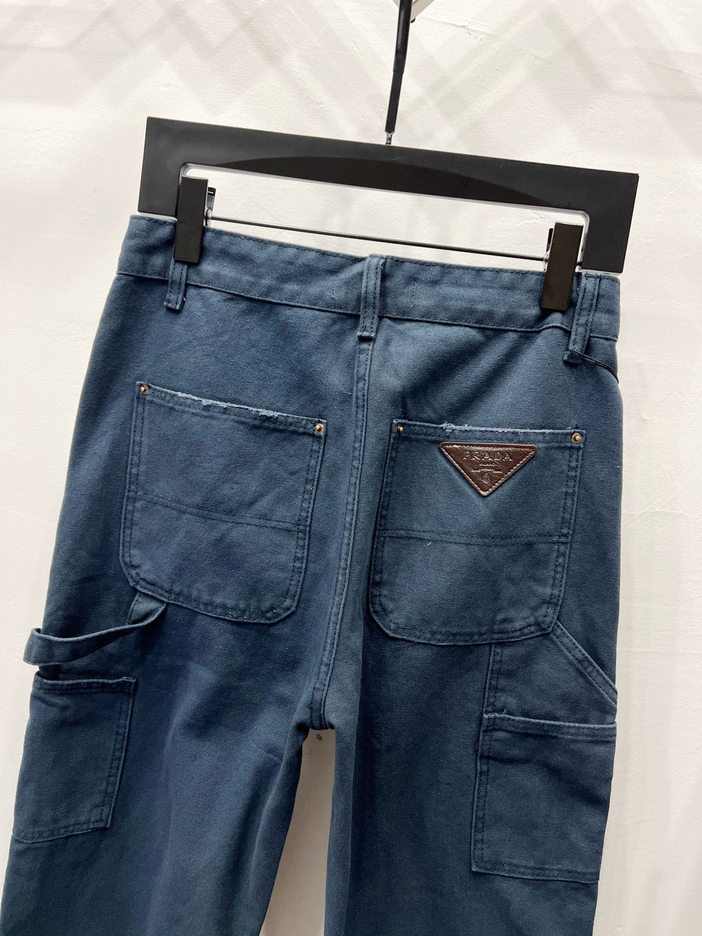 Dark blue denim pants with front patch pockets and triangular logo leather patch