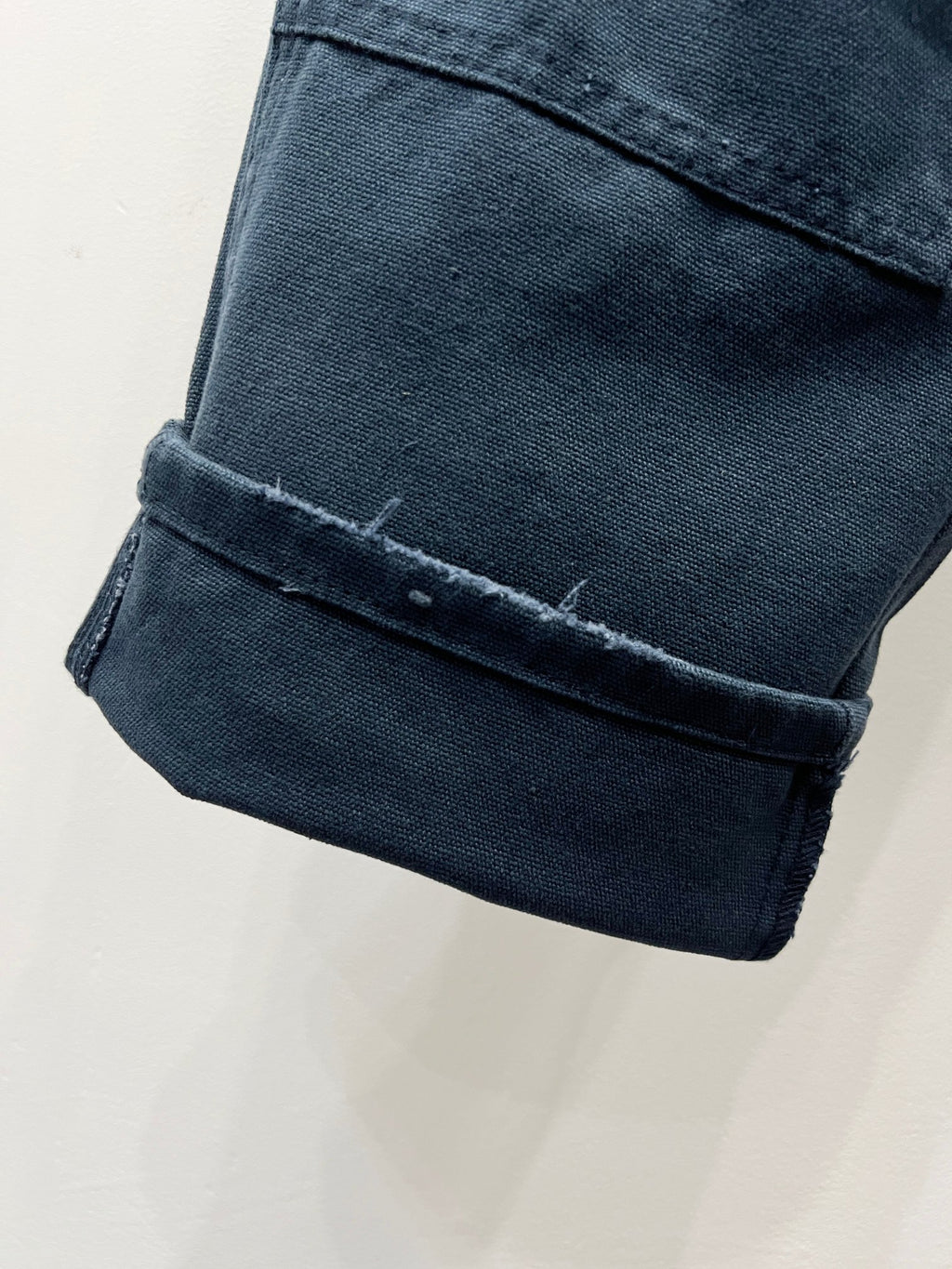 Dark blue denim pant cuffs with turned-up hem and stitched edging