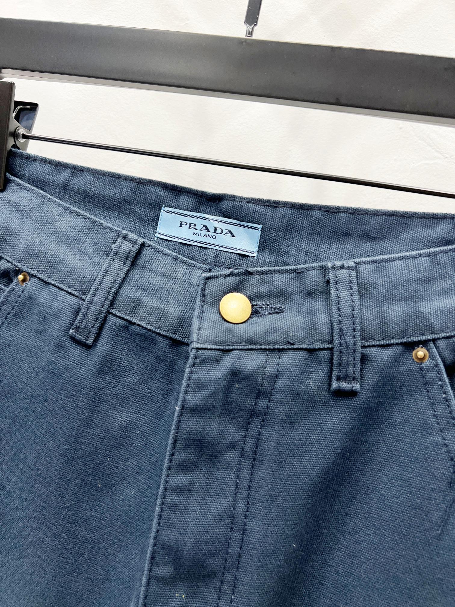 Dark blue denim waistband with brand logo tag and gold snap button