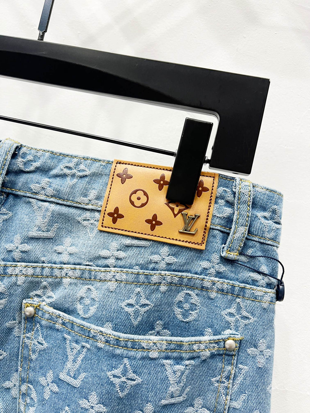 Light blue monogram denim waistband with tan patch label and button hardware