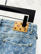 Light blue monogram denim waistband with tan patch label and button hardware