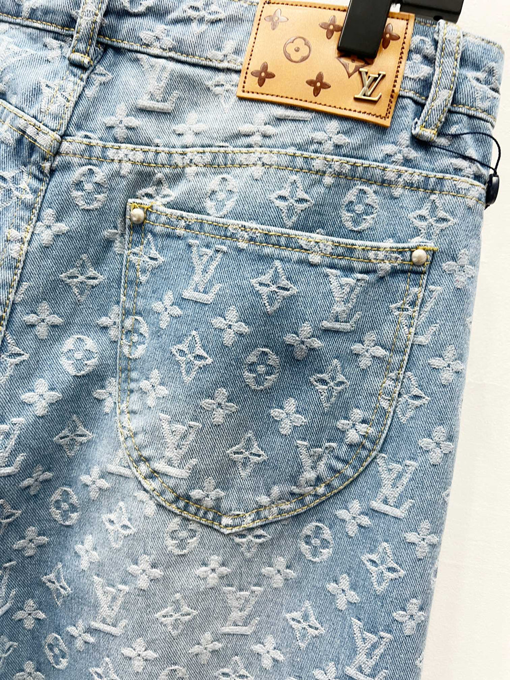 Light blue monogram denim pocket with tan patch label and gold-toned hardware