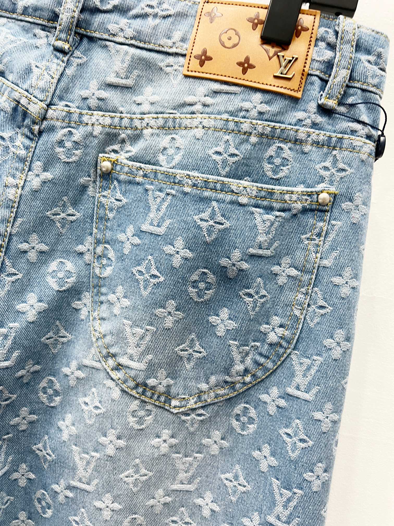 Light blue monogram denim pocket with tan patch label and gold-toned hardware