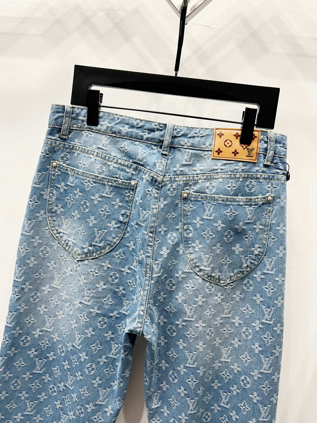 Light blue monogram denim jeans with curved front pockets and button closure