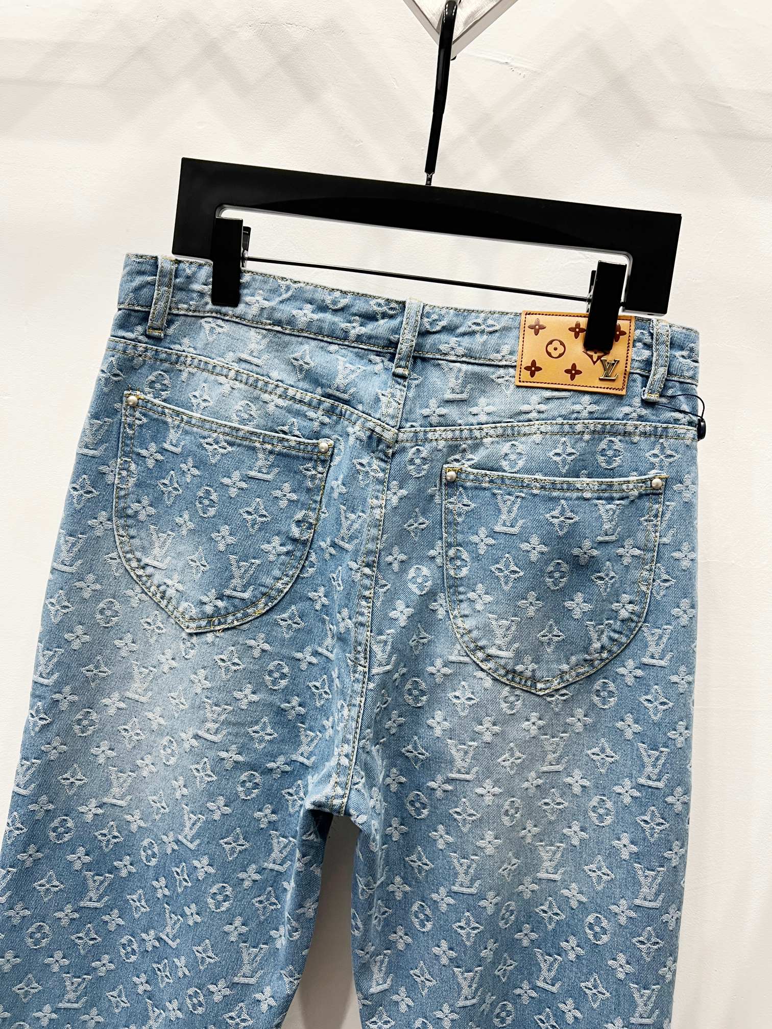 Light blue monogram denim jeans with curved front pockets and button closure