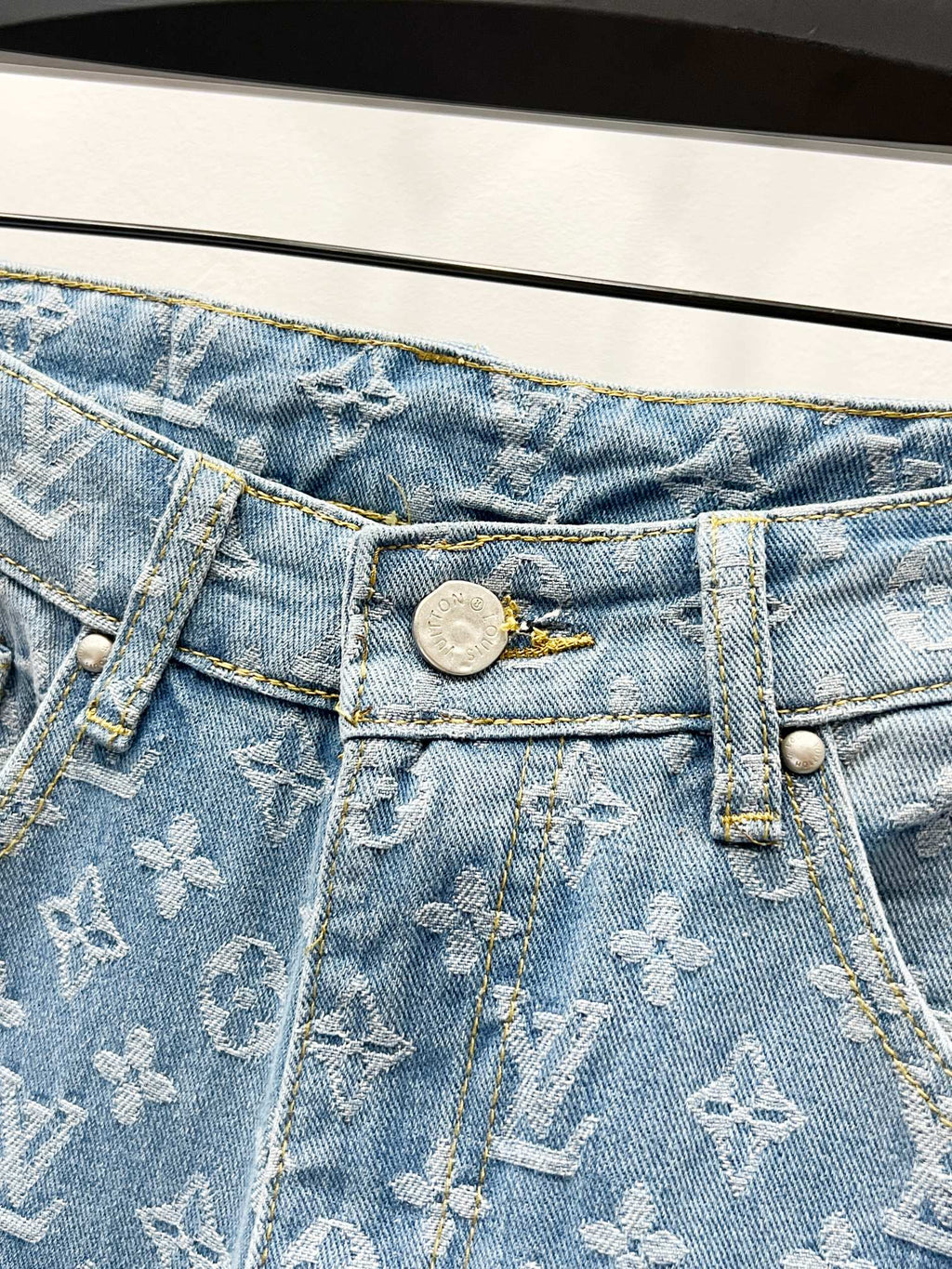 Light blue denim jeans waistband with button closure and monogram pattern