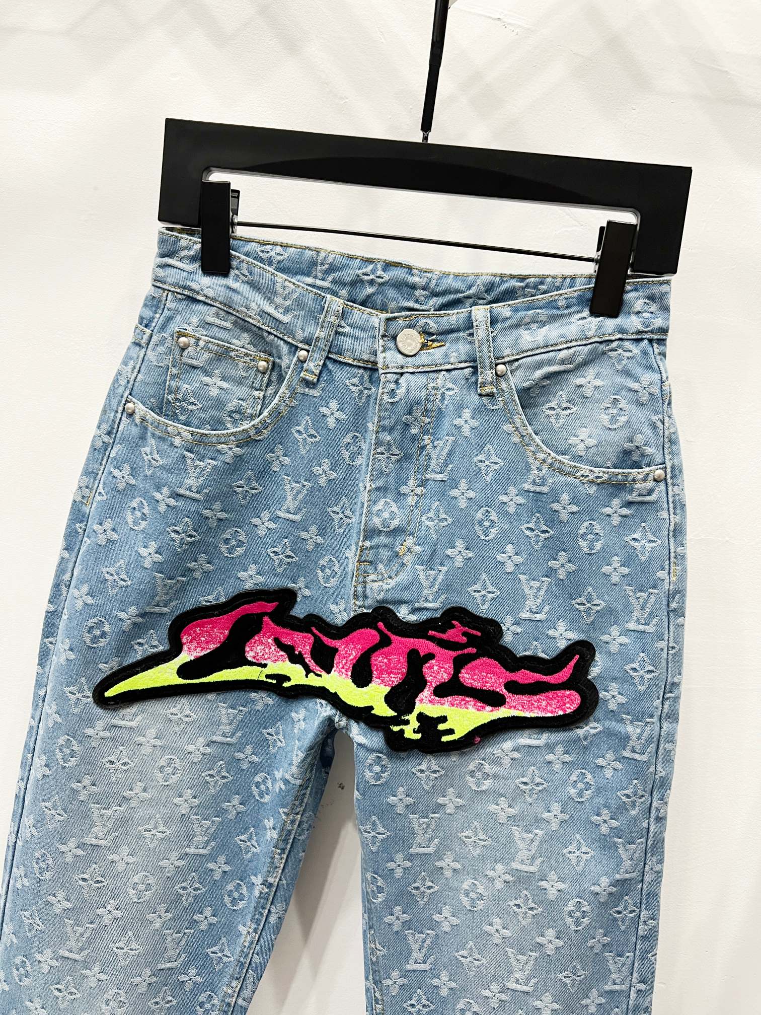 Light blue denim jeans with monogram pattern and graffiti patch on hip front