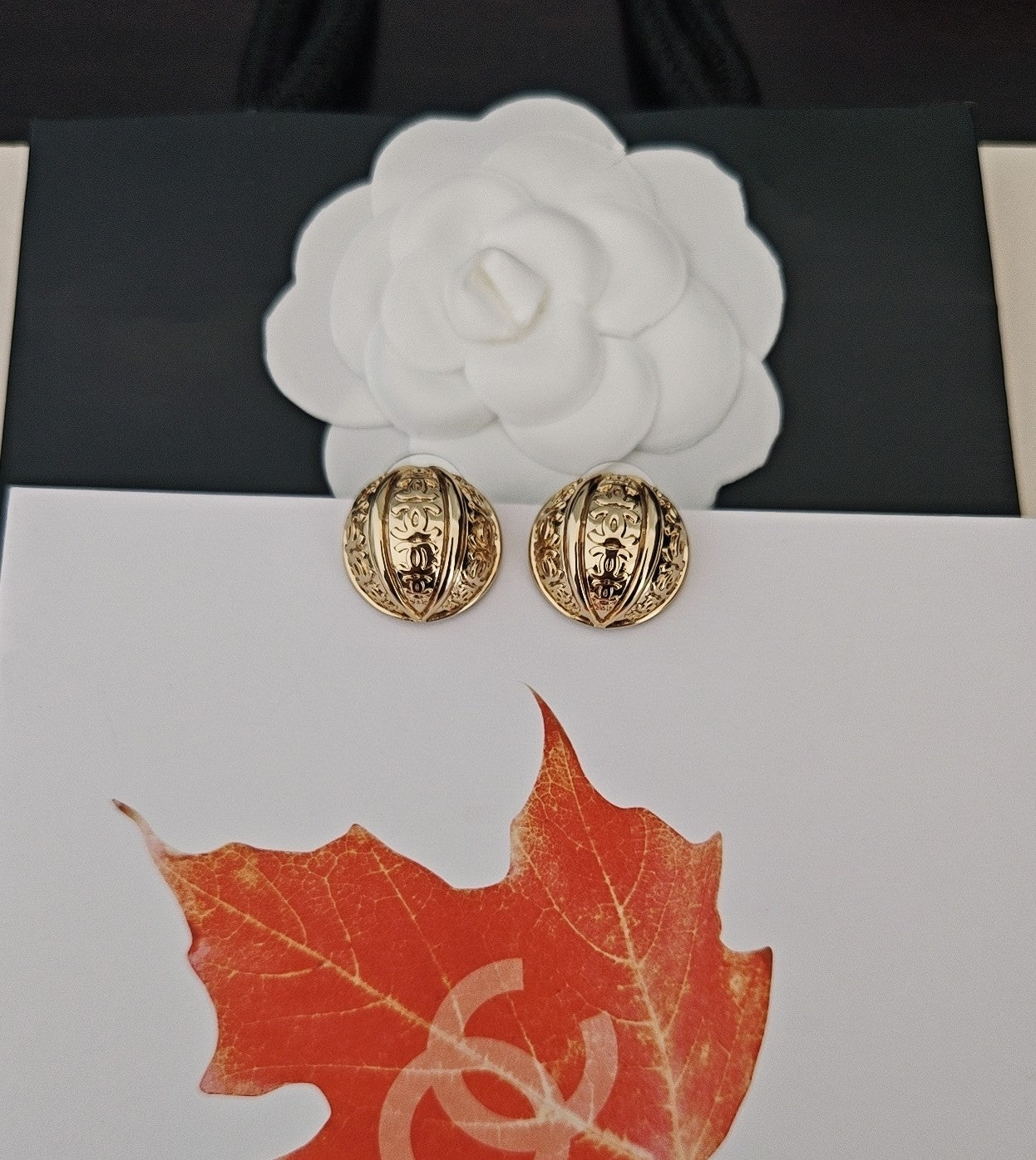 Round gold-tone stud earrings with embossed Chanel-style motifs