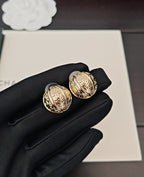 Round gold-tone stud earrings with ornate medallion faces