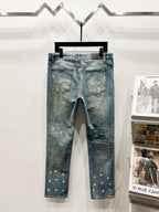 Light blue distressed denim jeans with scattered paint-like spots and ripped details