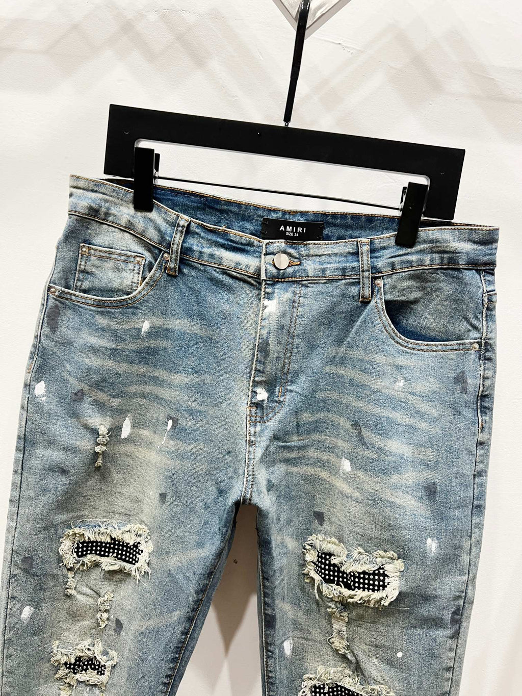 Light blue denim jeans with front rips and studded patch embellishments, mid rise