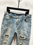 Light blue denim jeans with front rips and studded patch embellishments, mid rise