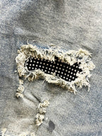 Distressed denim jeans patch with black fabric and small studs, frayed edges
