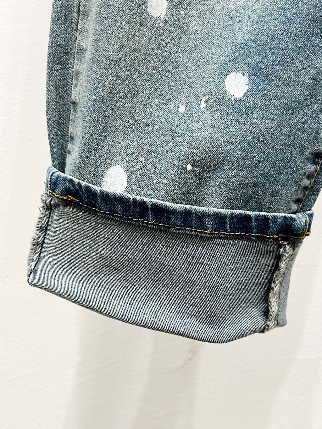 Light blue cuffed denim jeans with worn finish and scattered white spots