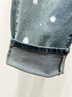 Light blue cuffed denim jeans with worn finish and scattered white spots