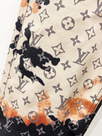 Monogram print fabric with beige base and dark accents plus orange abstract patches