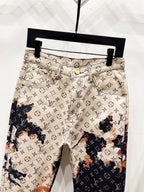 Monogram print trousers with beige waistband, front button, and side pockets