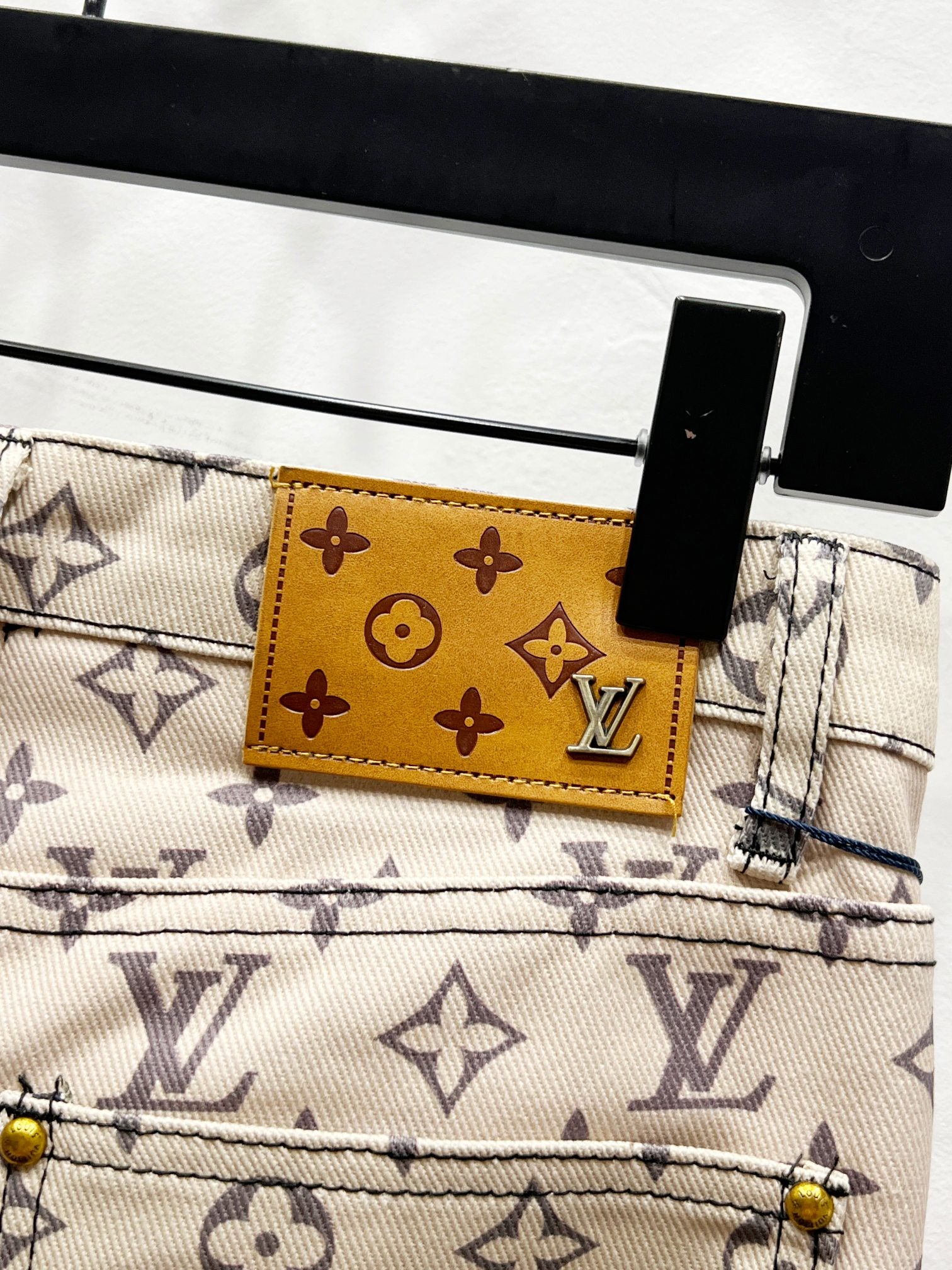 Waistband label patch on Louis Vuitton monogram print trousers in tan and gold tones
